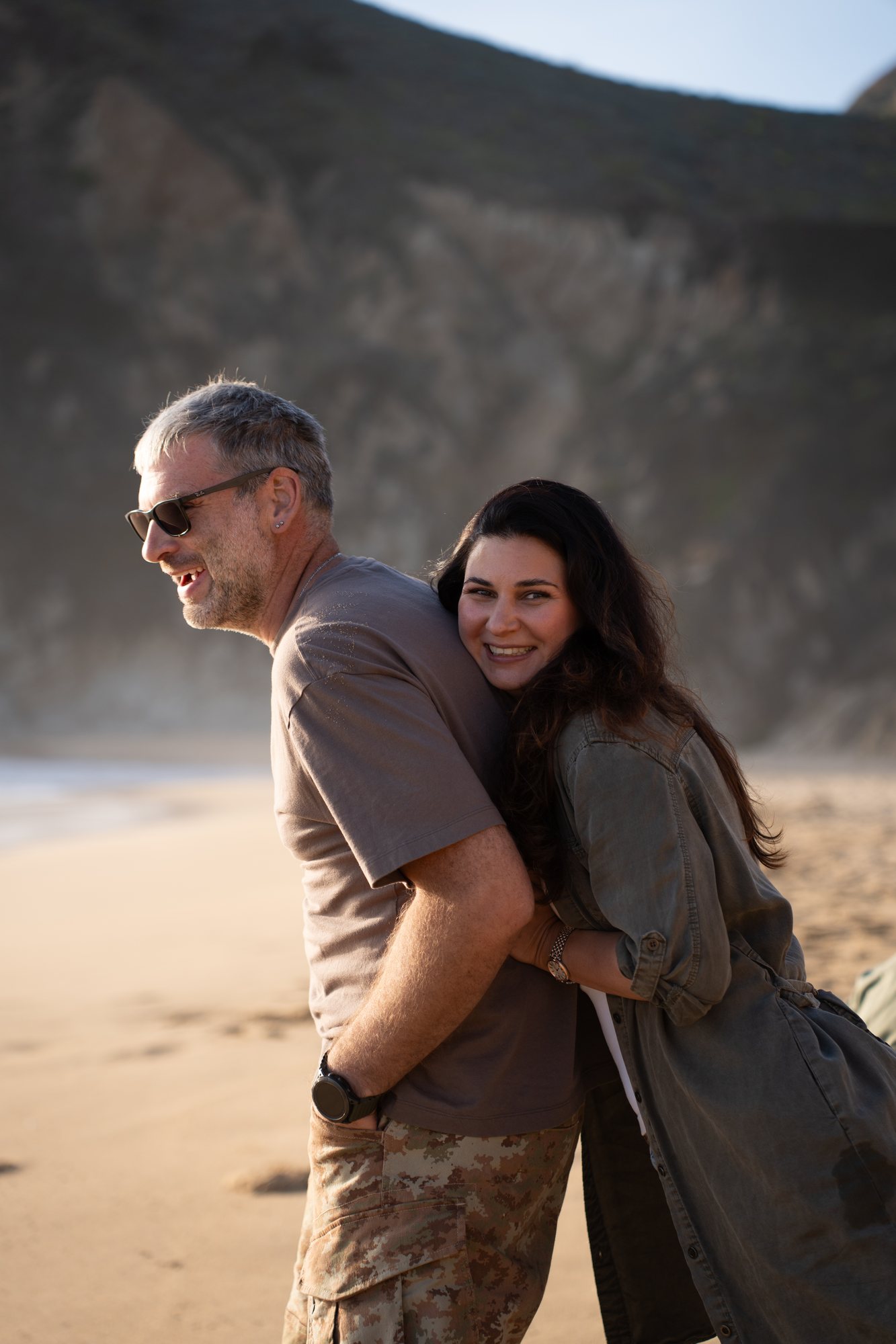 The couple laughing together on the sand