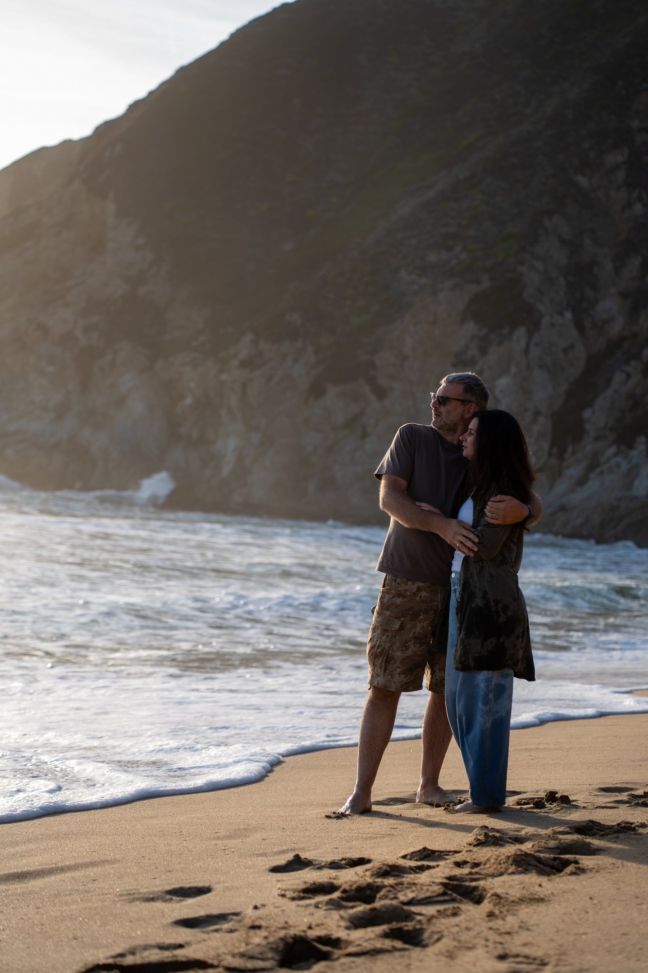 The couple leaning into each other by the sea