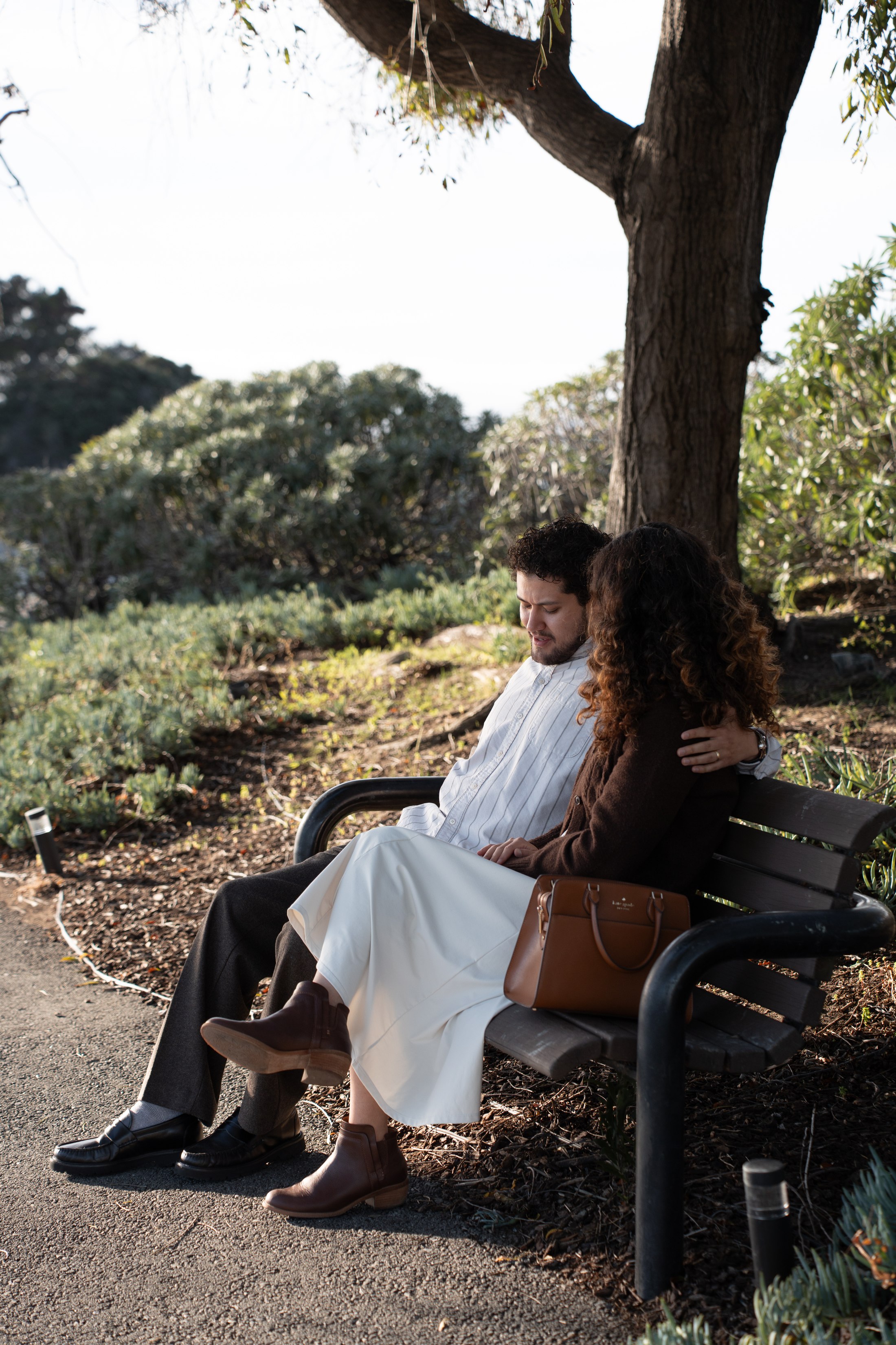 A couple sitting close together on a park bench