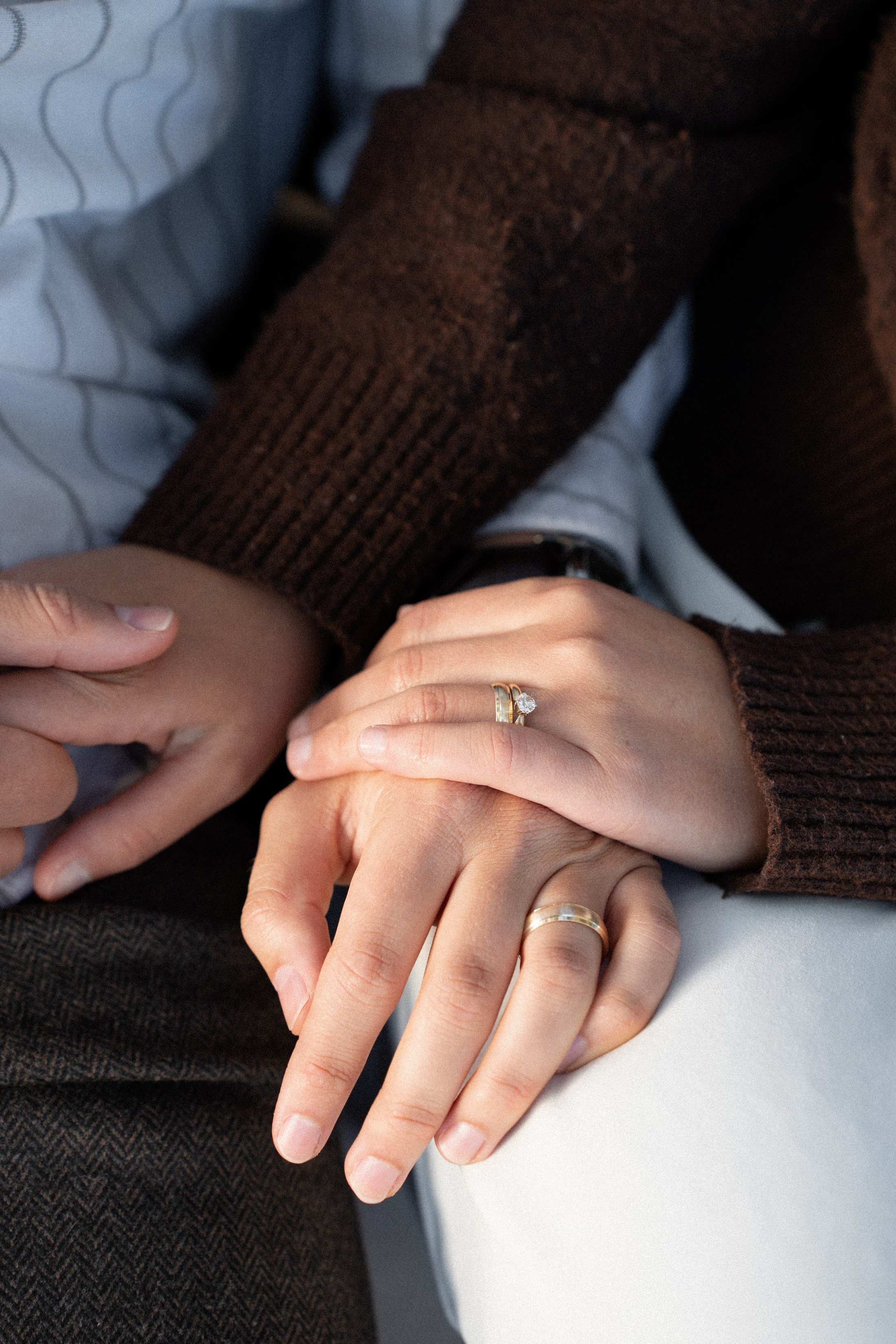 Their hands resting together, with an engagement ring in view