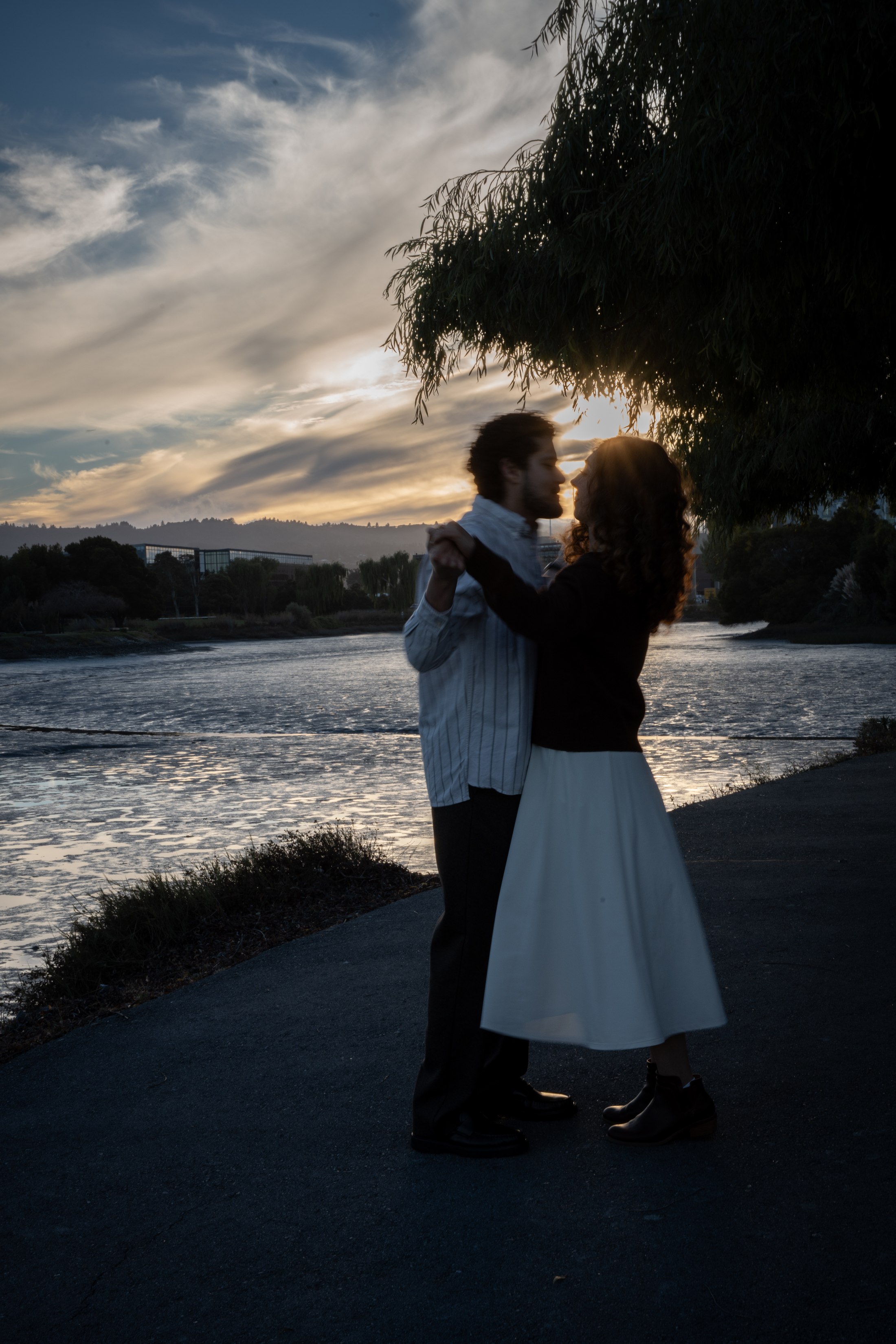 The couple embracing beside the bay at sunset