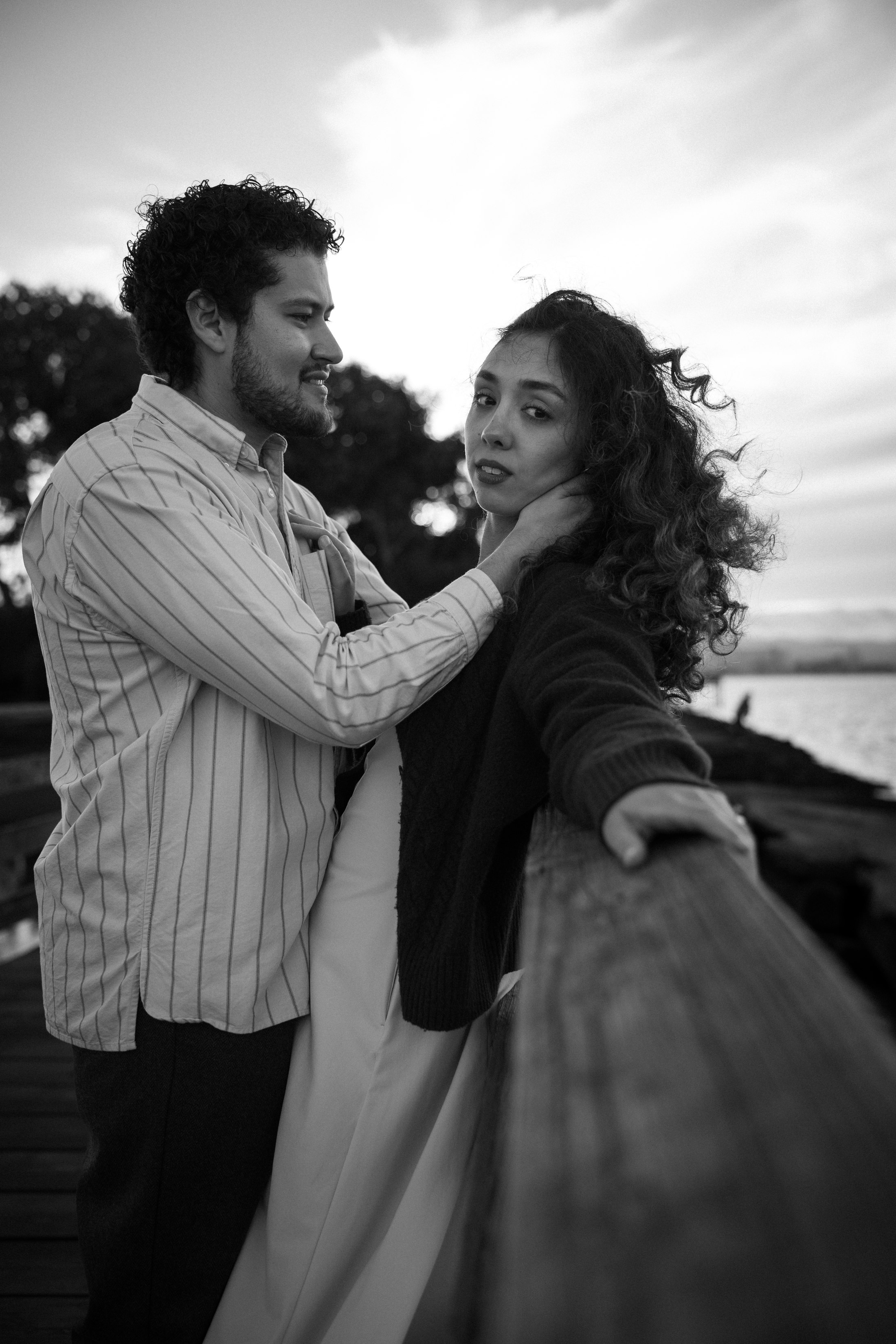 The couple sharing a quiet moment by the waterfront railing in black and white