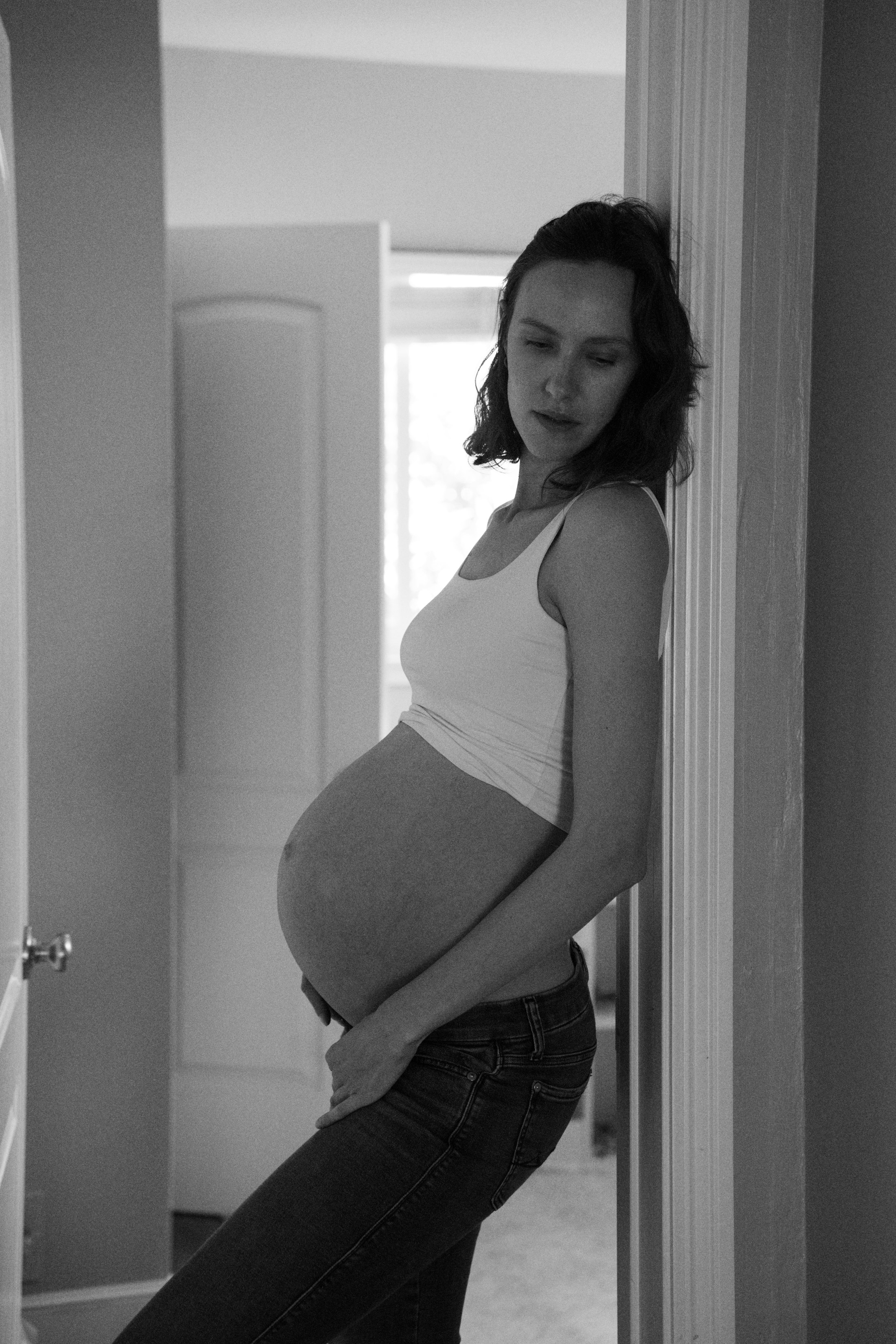 A black-and-white maternity portrait in a doorway