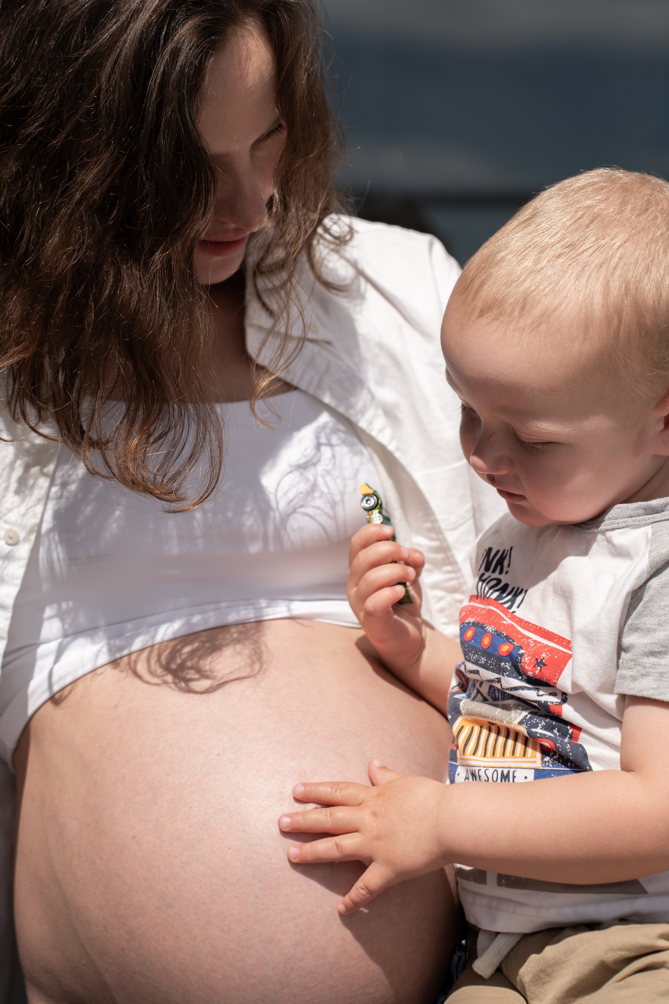 The child gently touching his mother’s belly