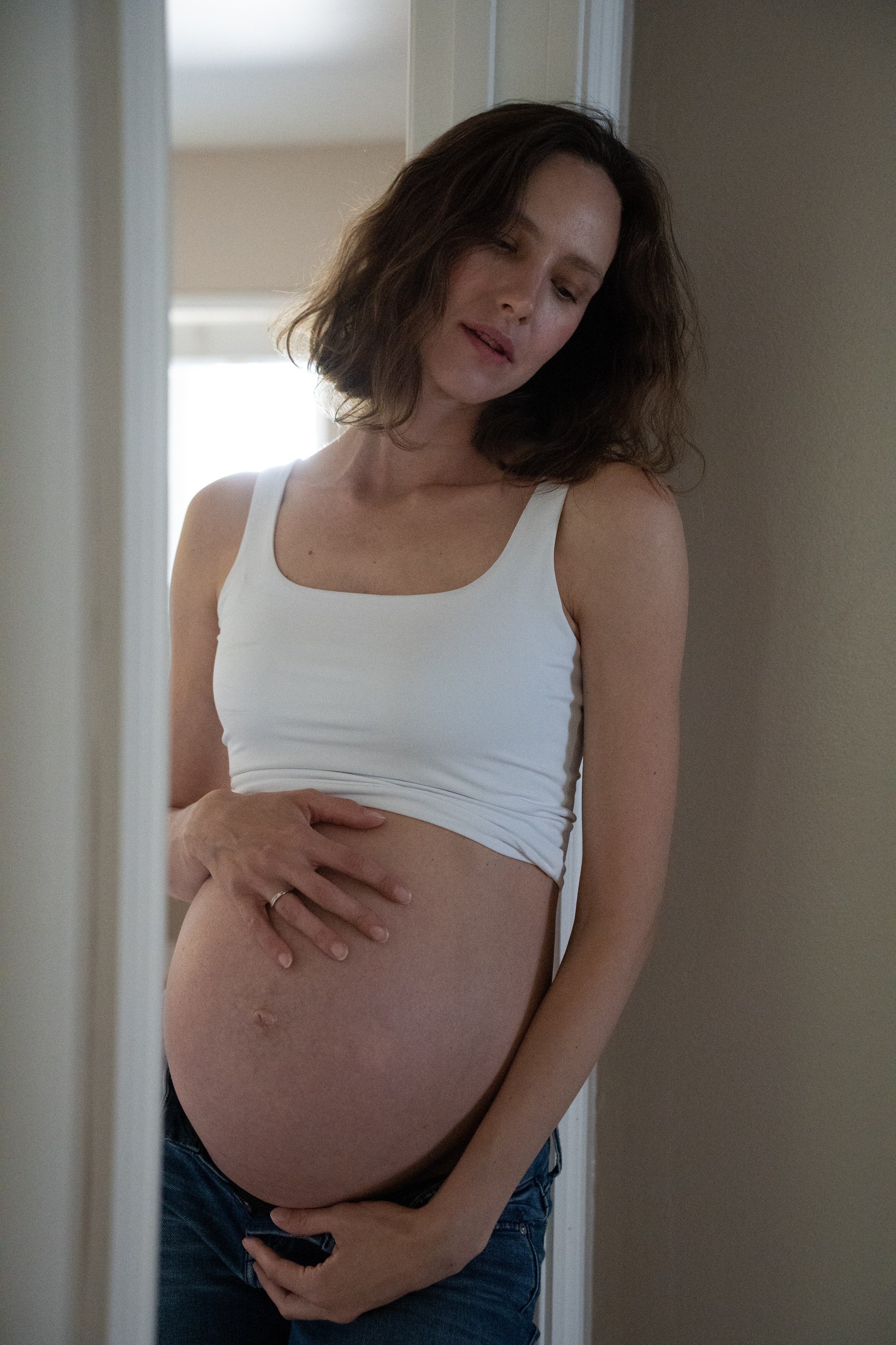 A calm portrait with both hands resting on her belly