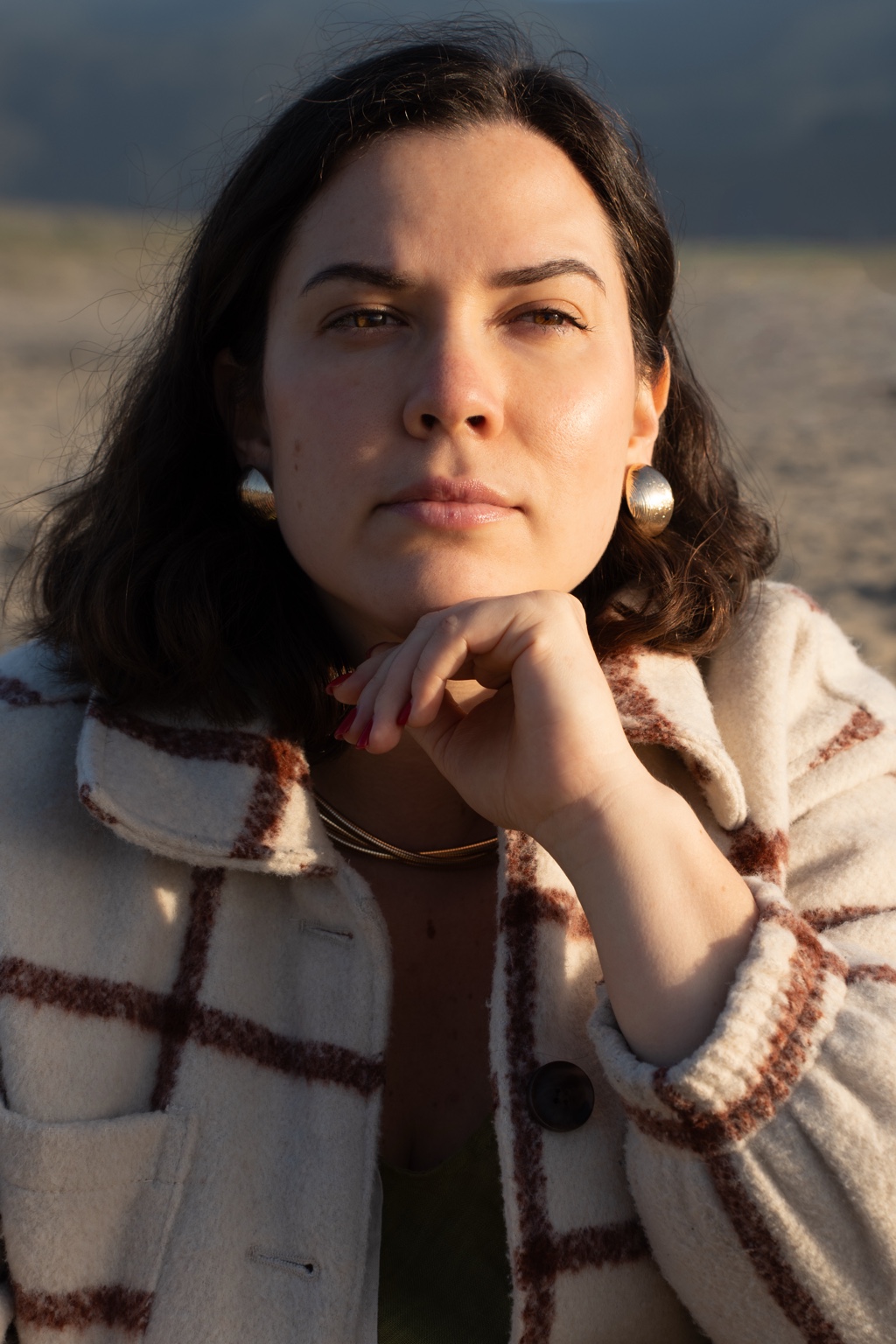 A close portrait in a plaid coat by the shore