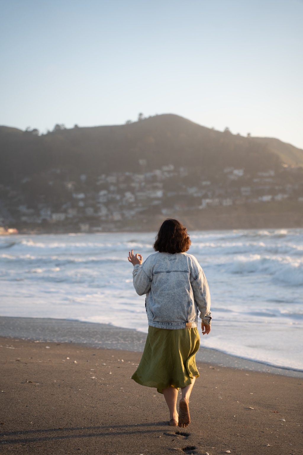 A woman walking toward the water in the evening light