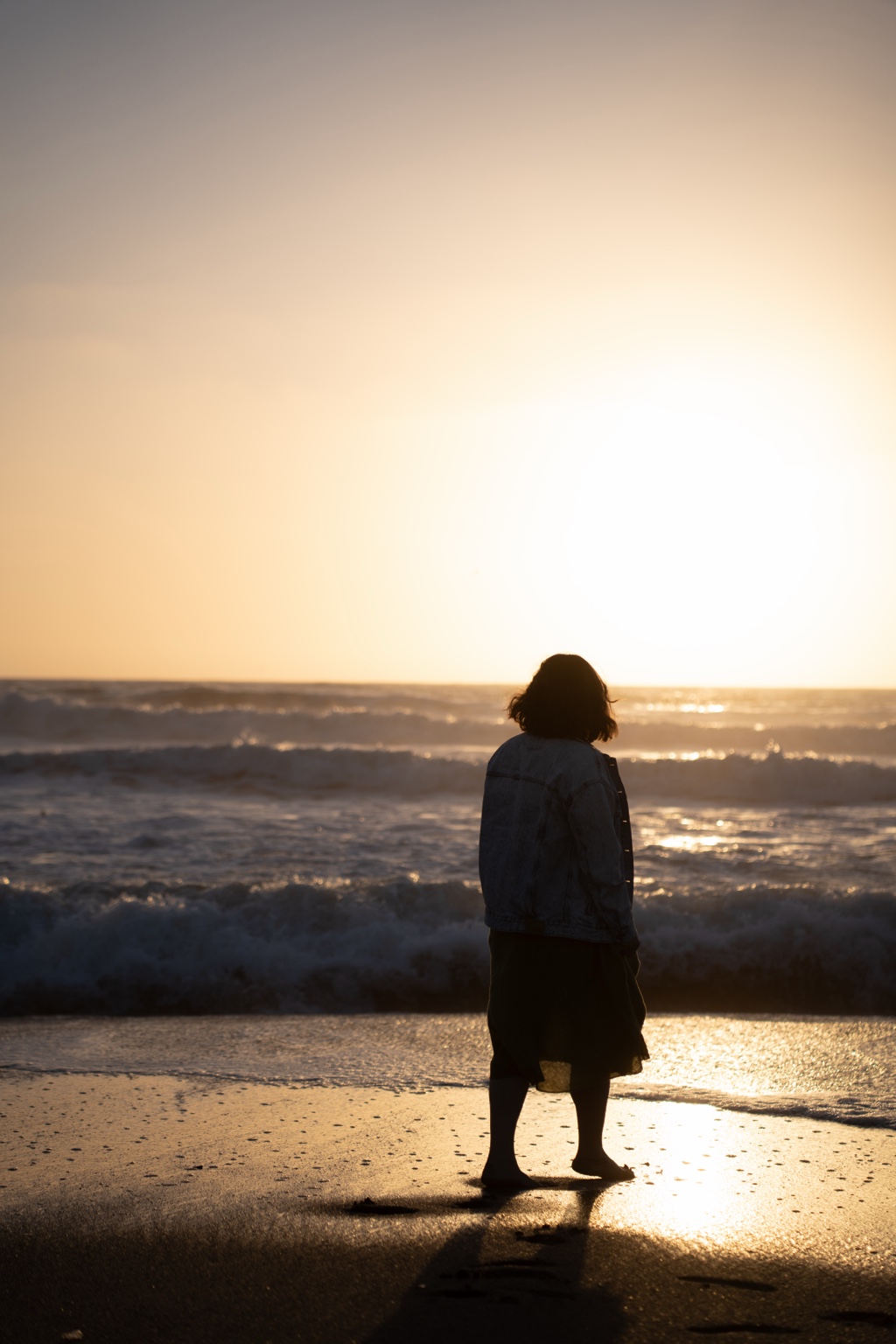 A silhouette facing the sunset and waves